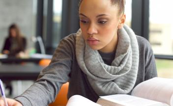 young teacher reading a professional book in library and taking notes