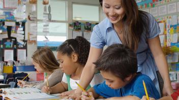 elementary teacher with small group of students reading textbook